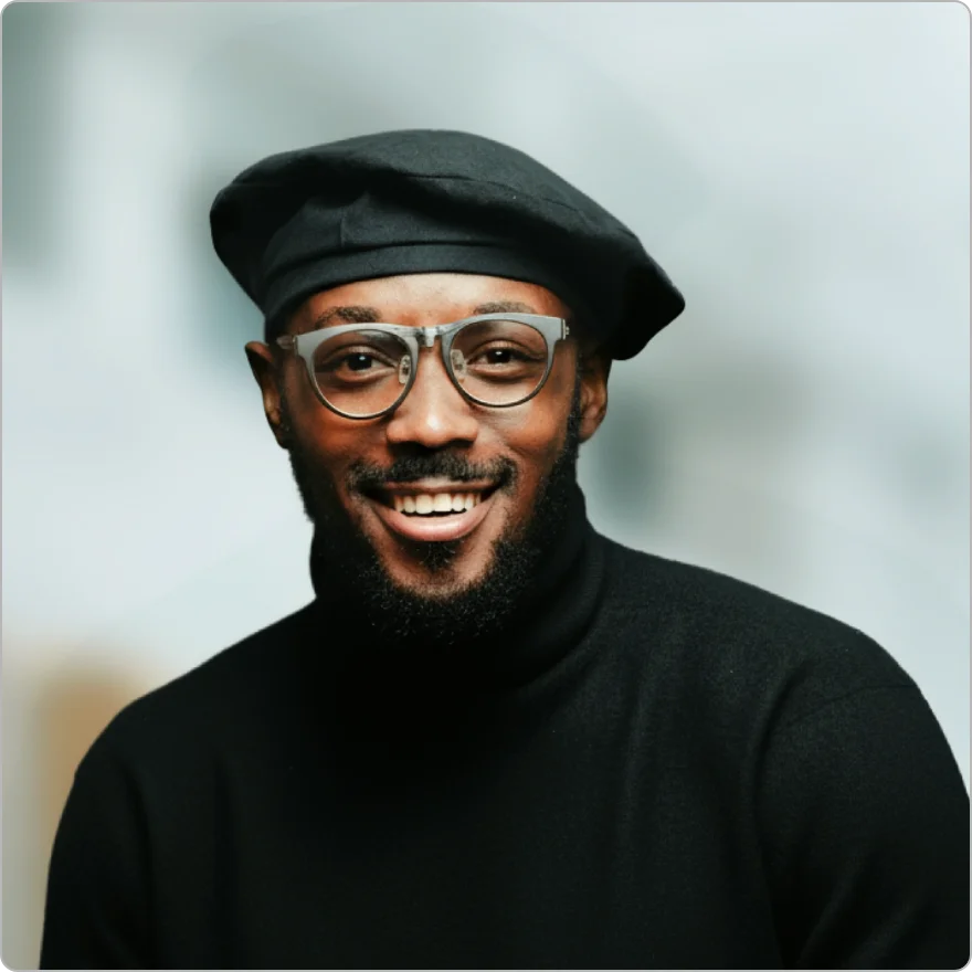 Professional man with glasses and a short beard smiling in a gray polo shirt.